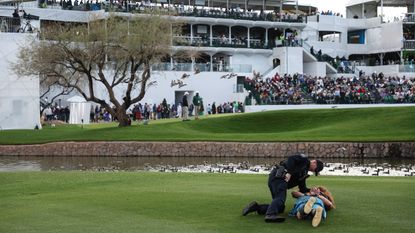 A security guard holds a fan down on the ground during the 2024 WM Phoenix Open