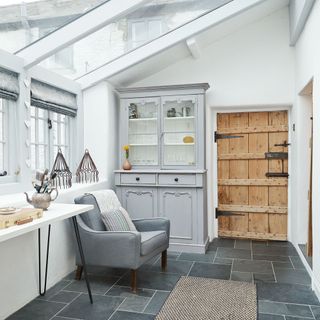 A small conservatory with grey slate floor tiles and a french dresser