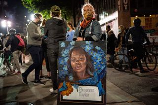 A demonstrator holds a painting of Breonna Taylor during a protest near the Seattle Police Departments East Precinct on June 7, 2020 in Seattle, Washington. Earlier in the evening, a suspect drove into the crowd of protesters and shot one person, which happened after a day of peaceful protests across the city.