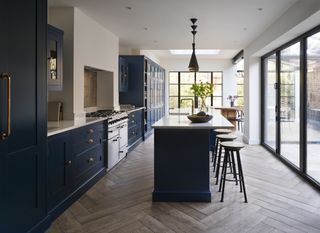 dark blue kitchen with island layout and bar stools