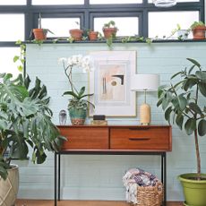 Mid-century room with painted brick wall, wooden sideboard and houseplants