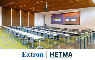 An empty classroom with the Extron and HETMA logos after their partnership.