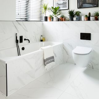 white bathroom with marble wall and floor tiles and black taps and finishes