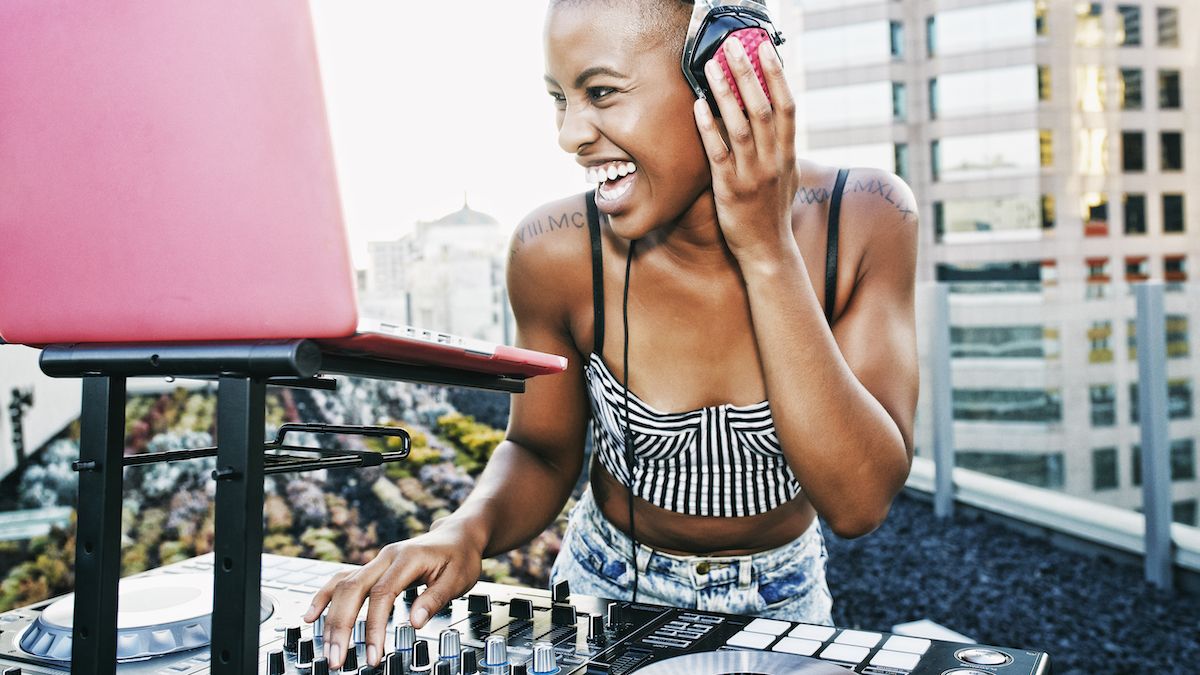 Woman DJing on a rooftop with a laptop in a pink case