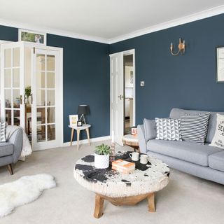 living room with blue dark walls coffee table with coffee mug and couch with cushions