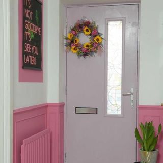 hallway with white door wreath and potted plant