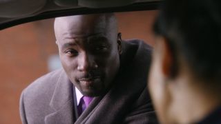 Mike Colter looking into a car window.