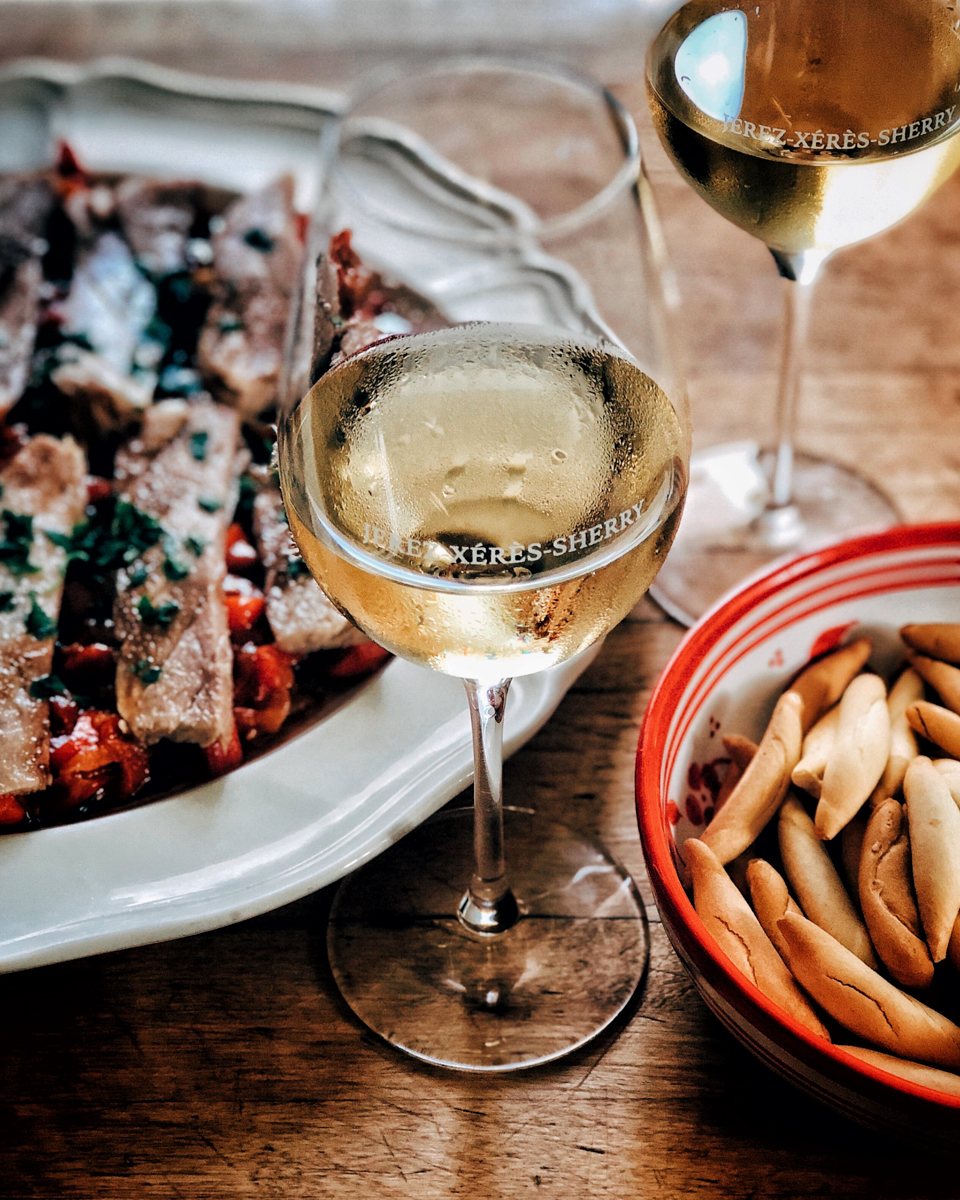 Photo of a wine glass alongside plates of food