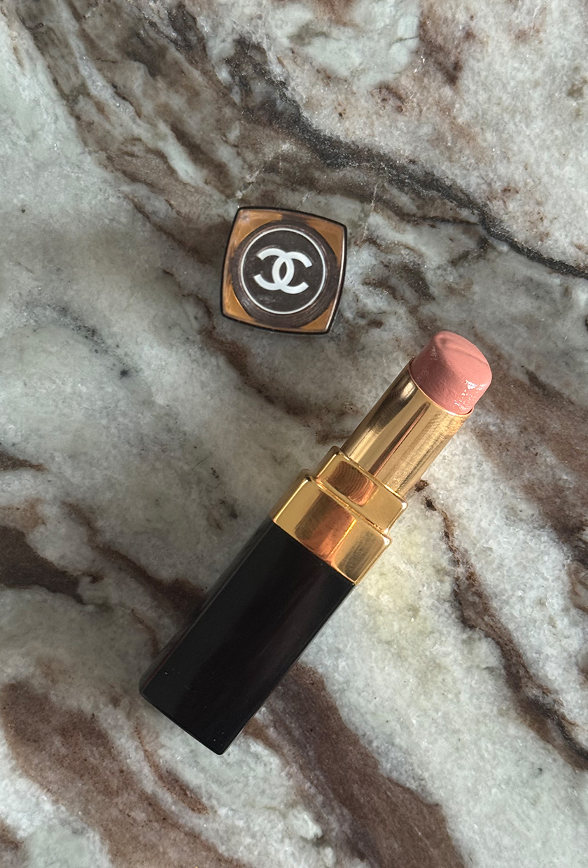 A chanel rouge coco flash lipstick placed on a brown toned marble surface
