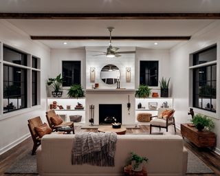 A white living room with neutral furniture and recessed ceiling lighting.