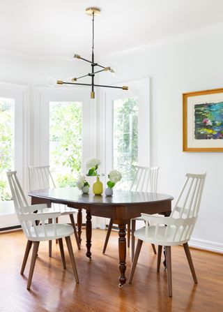 A dining room with a wooden table and white chairs