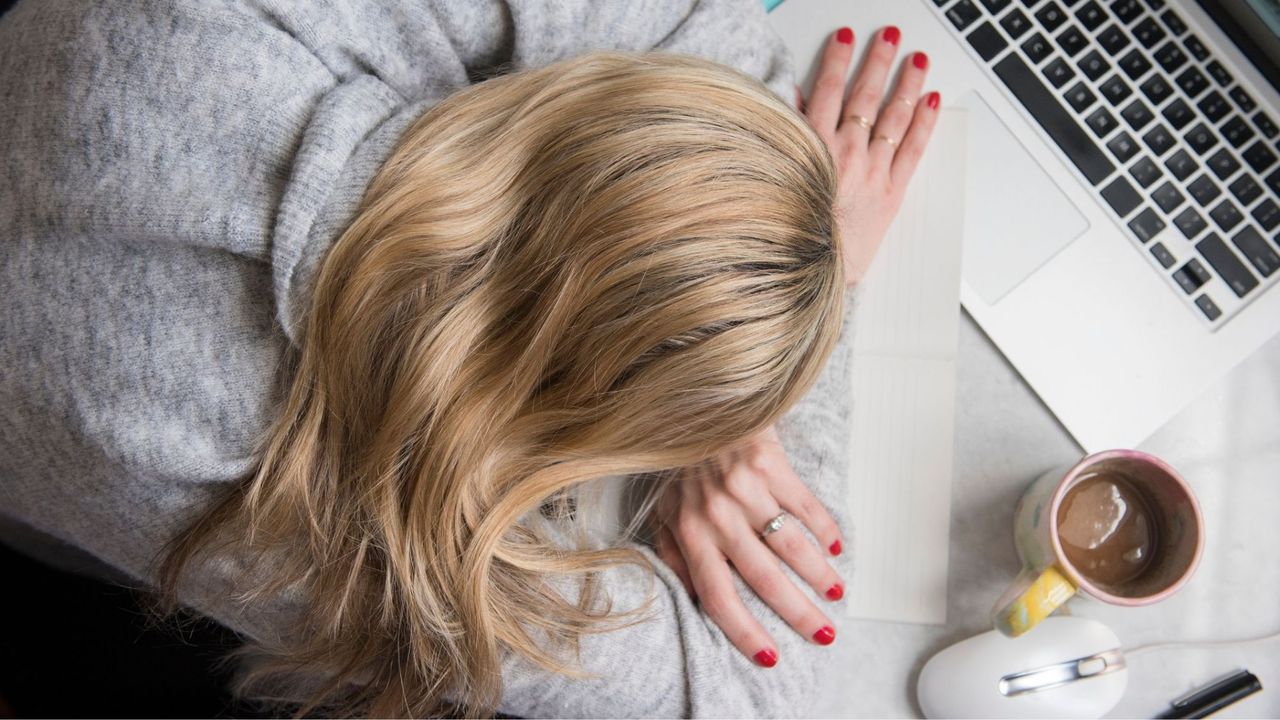 Woman with head on desk stressed figuring out the difference between stress vs anxiety 