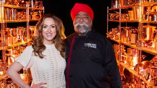 Natalie Cassidy and Tony Singh standing side by side against a black background in front of rows of pots and pans.