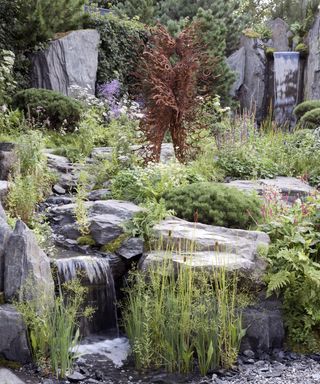 A mountain style garden with a natural pool and artistic sculpture