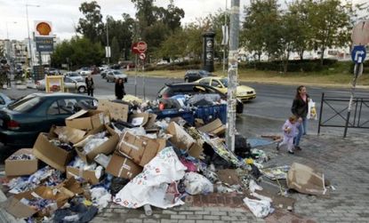 People walk past a heap of garbage in an Athens suburb: Between a trash collectors' strike and the stress of ongoing protests, Greece may be on the verge of a health crisis.