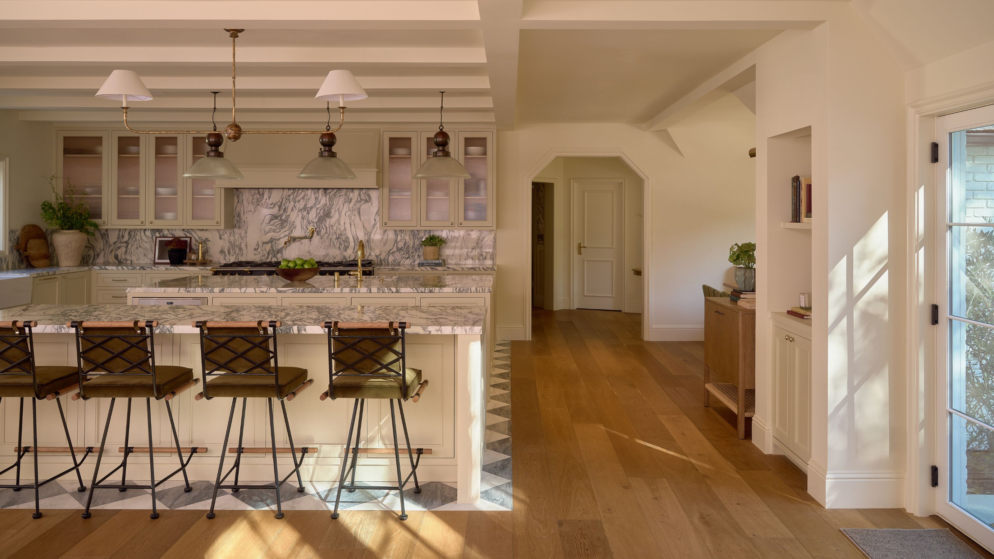 a large open plan neutral kitchen with both wooden and checkerboard flooring to zone the areas