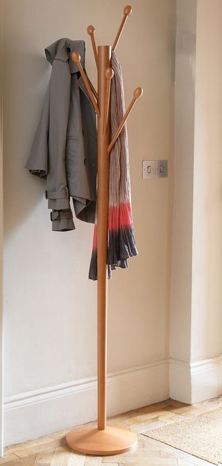 Tree Coat Stand with warm wooden tones, in a hallway with a coat and scarf hanging off it