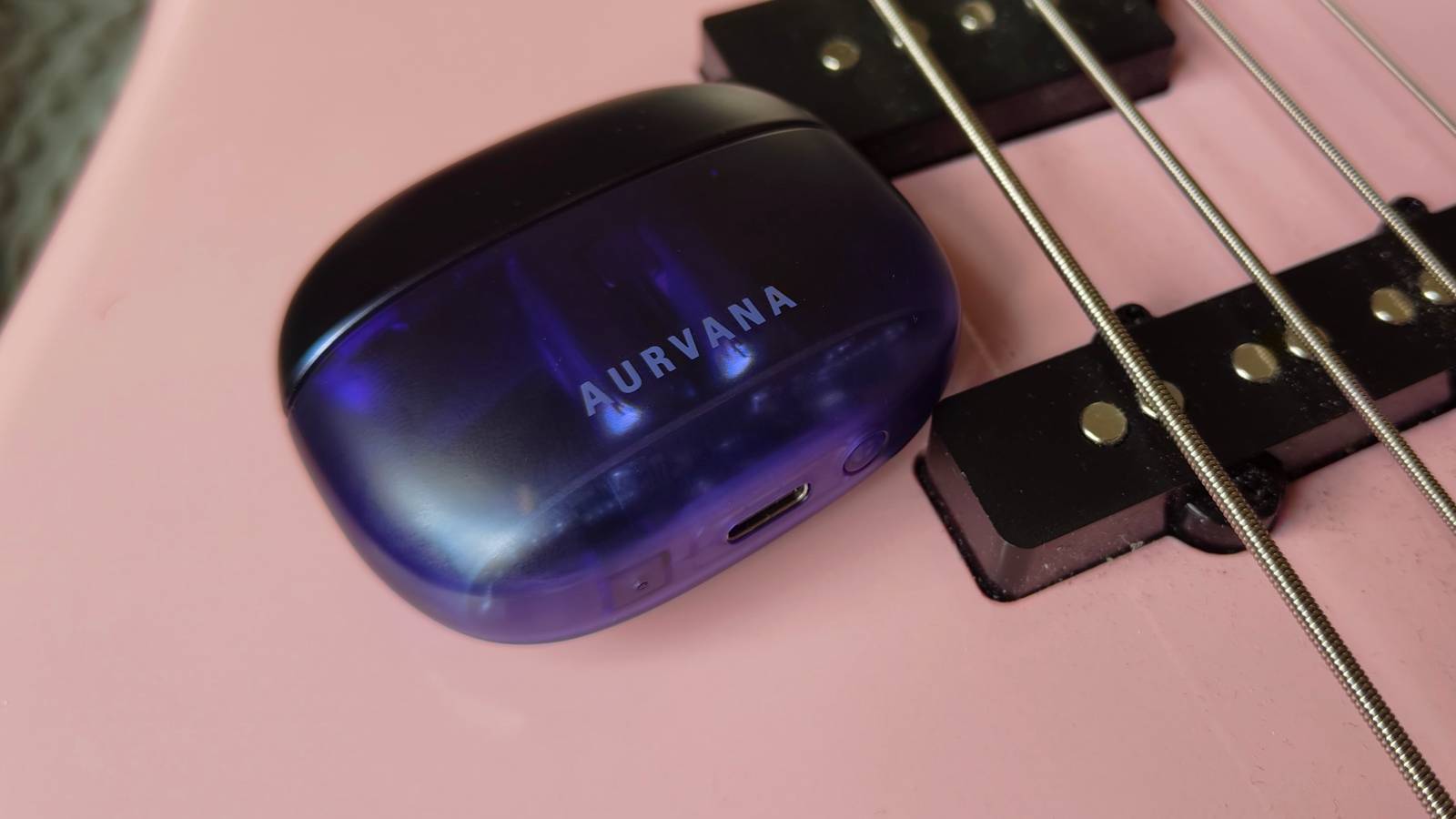 The Creative Aurvana Ace 3 case on a pink bass guitar.