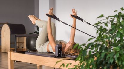 A woman on one of the best at-home Reformer Pilates machines