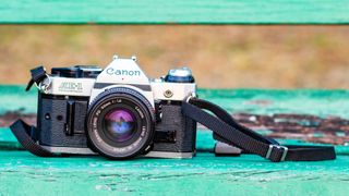 The Canon AE-1 camera sitting on a green bench