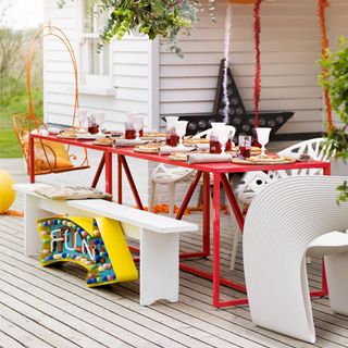 garden area with wooden floor and red table and white chair and bench