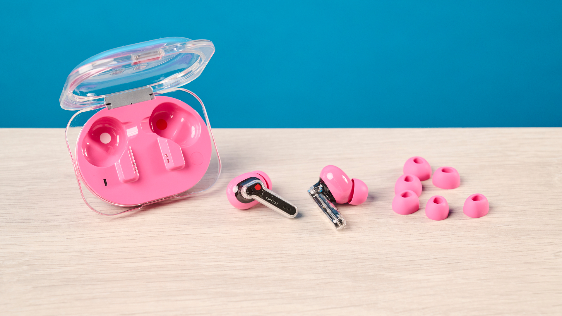 The Nothing Earbuds (3a) in pink, on a wooden surface