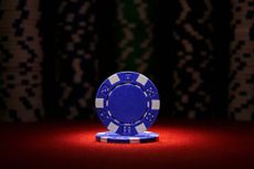two blue poker chips, stacked under a spotlight