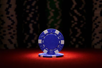 two blue poker chips, stacked under a spotlight