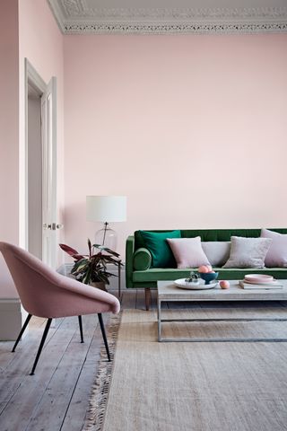 pink living room with green couch, limed floor bars, coffee table, lamp, pink armchair, pink cushions