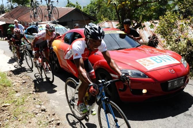Riders pass the broken-down commissaire vehicle