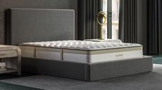 Saatva Memory Foam Hybrid Mattress on a gray bed base against a gray wall. 