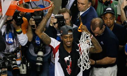 Injured Louisville guard Kevin Ware celebrates after he cut down the net after his team beat Michigan 82-76.
