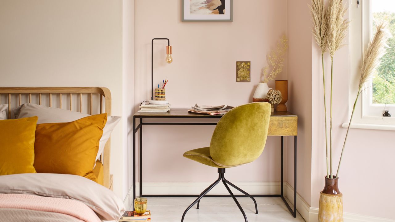 small bedroom colour ideas, off white and pale blush walls, wooden bed, white painted floor boards, wood and metal desk, velvet desk chair, turmeric coloured pillows, blush bedding, pampas in vase, artwork 