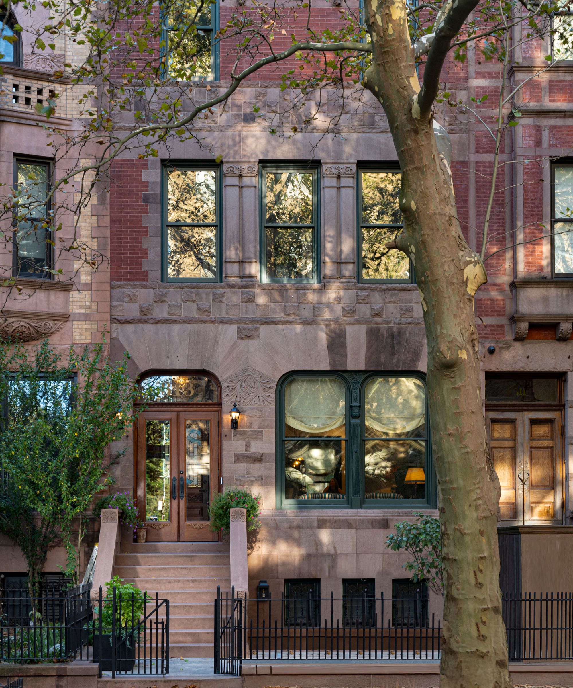 a traditional Hamilton Heights five story brownstone with a large tree set outside the steps