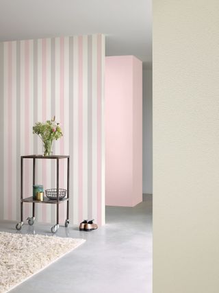 Pink and grey striped wallpaper with wheeled table and potted plant on grey concrete style floor with cream rug (Part of the Nordic Elegance range at Galerie Wallcoverings)