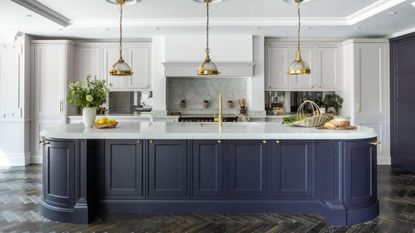 A white kitchen with a blue kitchen island. Three hanging pendants above.