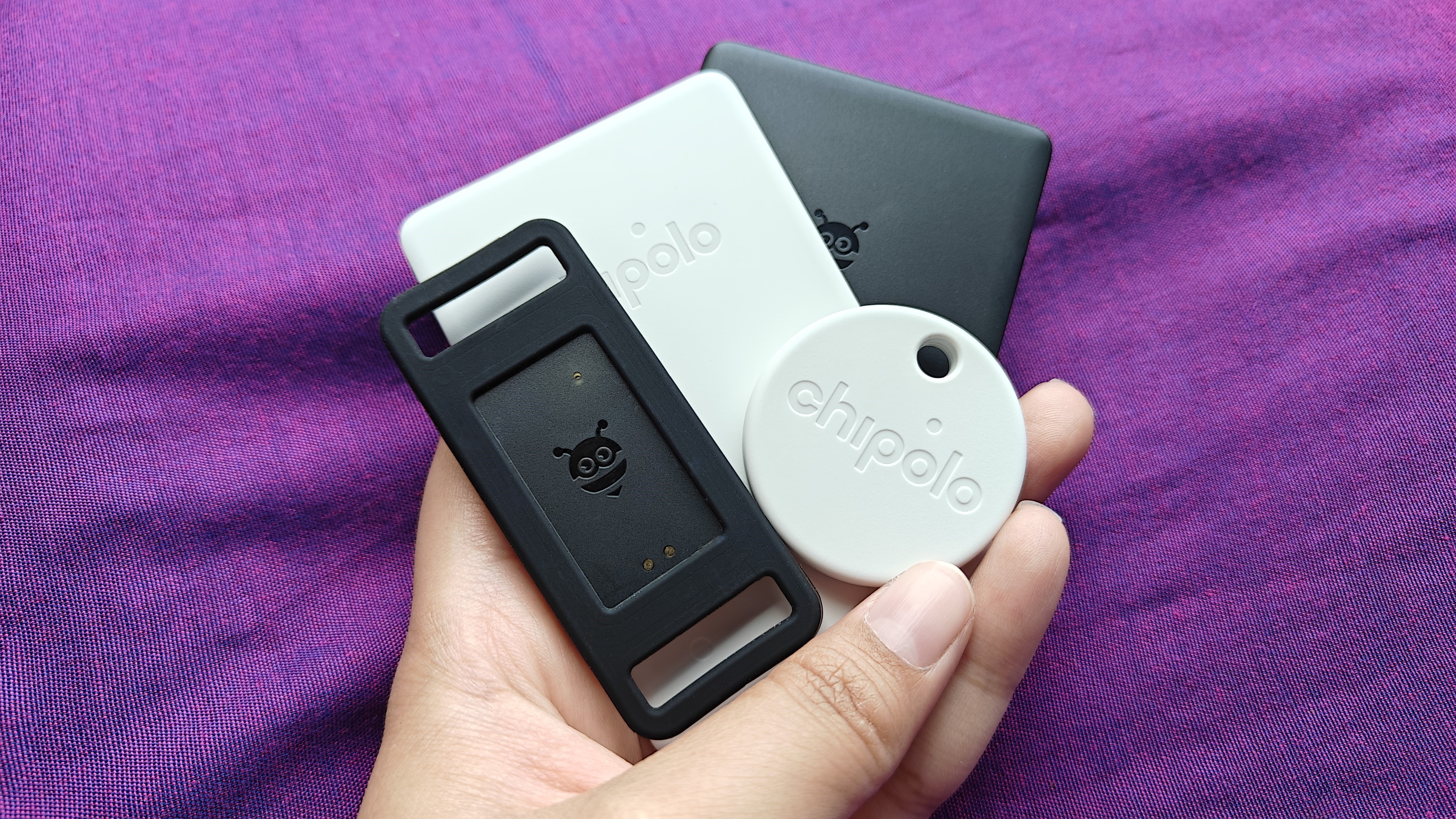 Various Google Find My Device Bluetooth trackers from Chipolo and Pebblebee held in one hand.