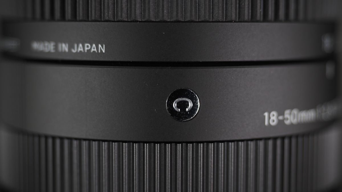 The Sigma 18-50mm f/2.8 DC DN | C Canon RF lens on a wooden surface against a dark background with moody lighting