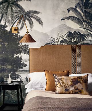 Cozy bedroom ideas with monochrome tropical print wallpaper and pale ochre headboard.