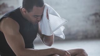 A man at the gym wiping sweat from his brow with a towel