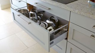 Gray blue kitchen with pan drawer directly under the hob to avoid a common kitchen design mistake of not having the right accessible storage