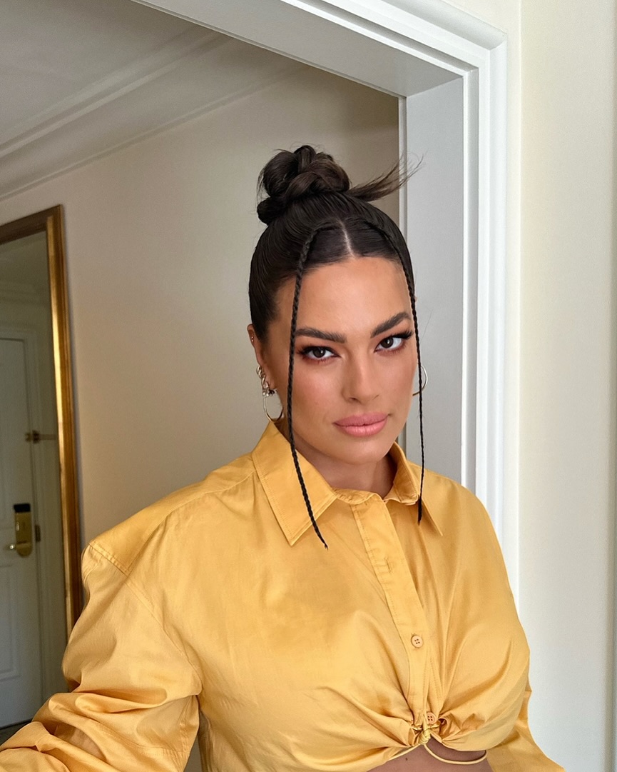 Ashley Graham wears a sleek top knot with face-framing accent braids by Justine Marjan