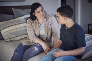 mum talking to teen son while sitting on the bed