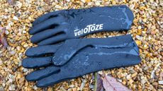 Velotoze neoprene gloves on some gravel with water droplets on them