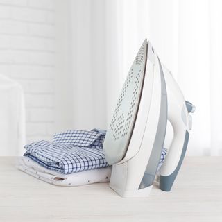 Iron and folded clothes on ironing board