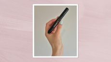 A close-up of Digital Beauty Writer, Naomi Jamieson's hand holding the The Victoria Beckham Beauty Concealer Pen with TFC8&reg;, in front of a white wall. A swatch of the product can also be seen on the back of Naomi's hand. The image is features in pastel purple, watercolour paint-style template