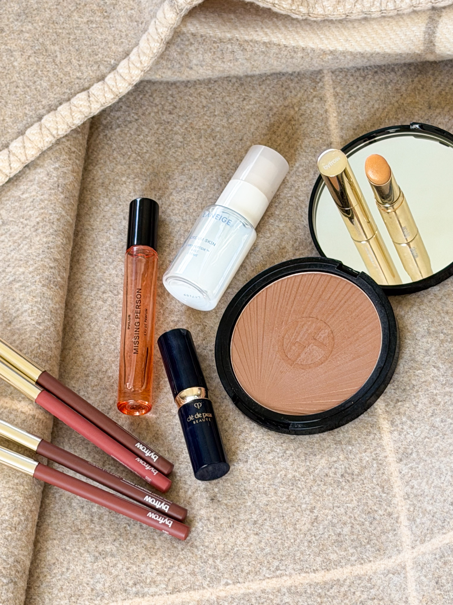 A selection of Victoria Magrath's top beauty products on a beige blanket
