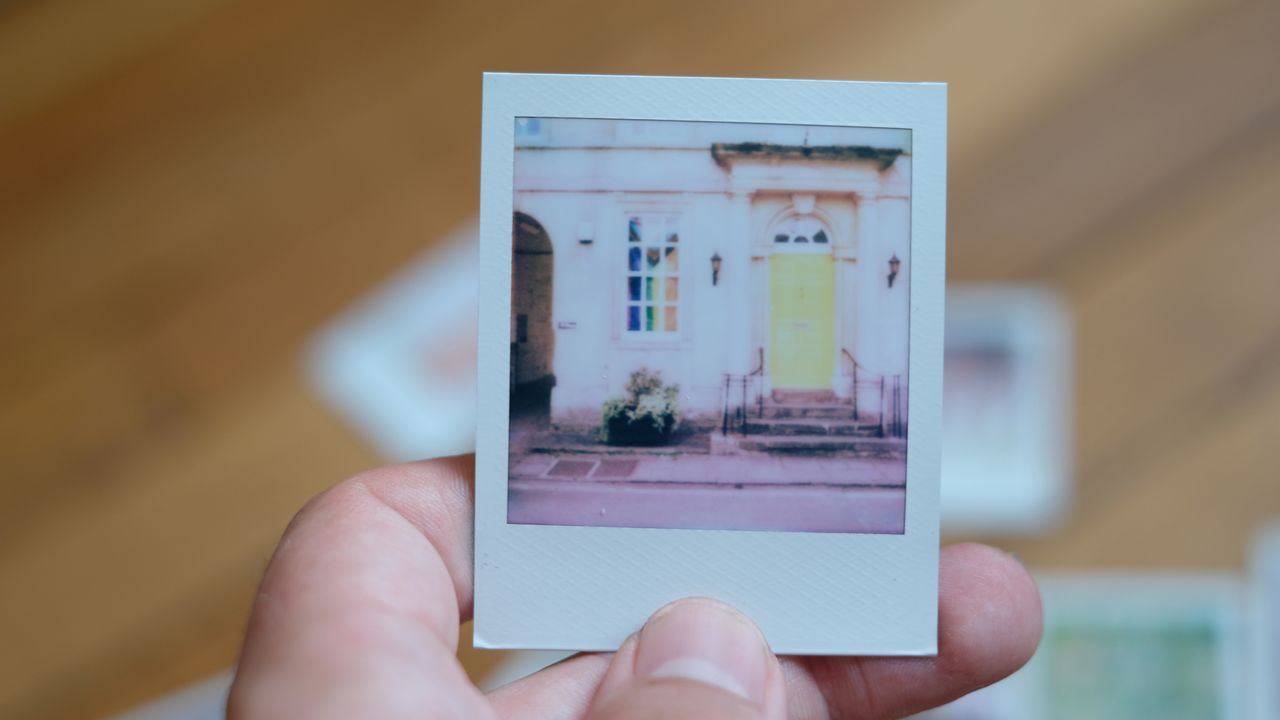 Photograph of prints made with Polaroid Go Gen 3 showing a yellow door next to a Pride flag, image is very bright