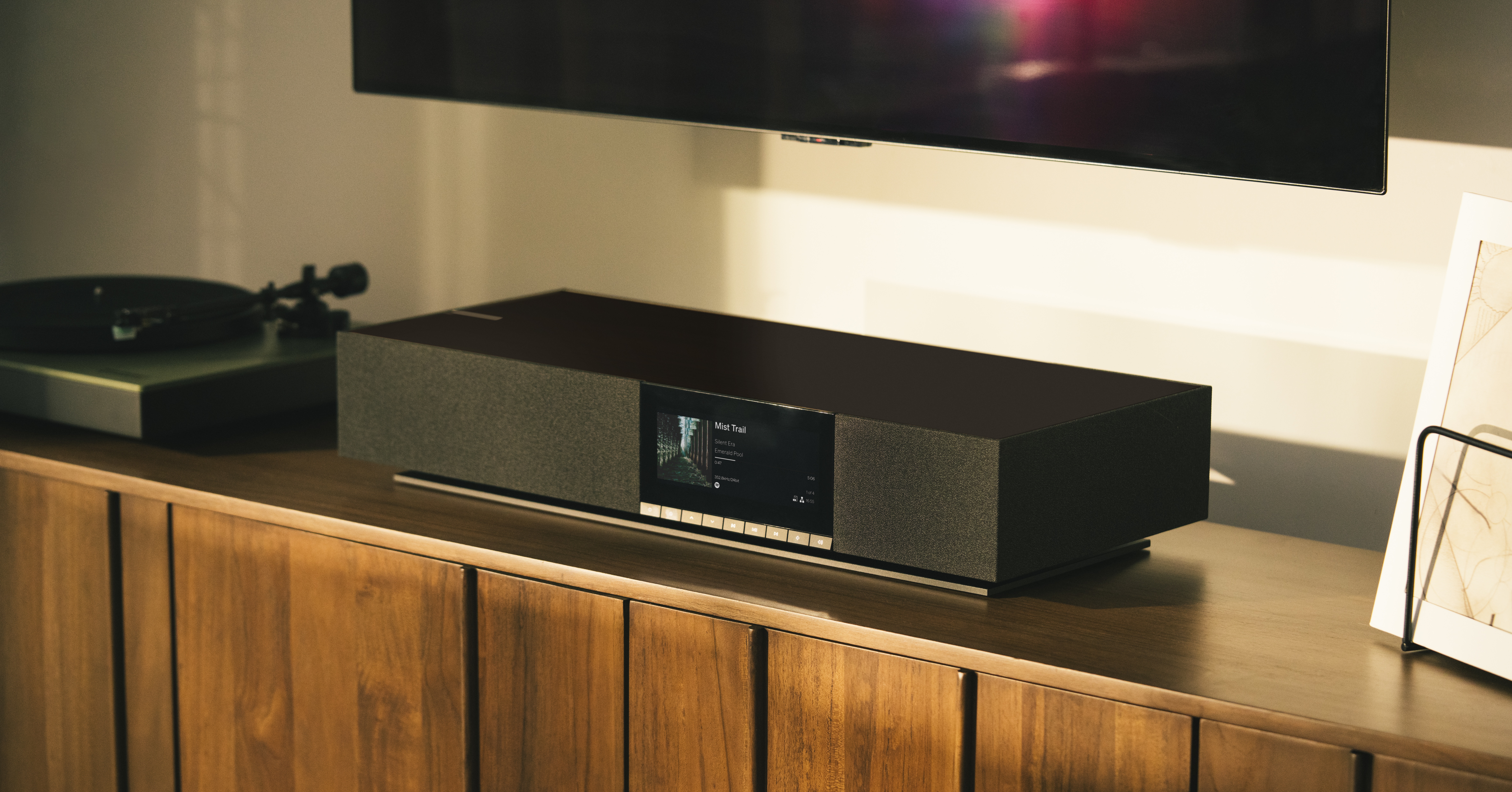 Cambridge Audio Evo One Midnight on a side table, under a TV, next to a turntable