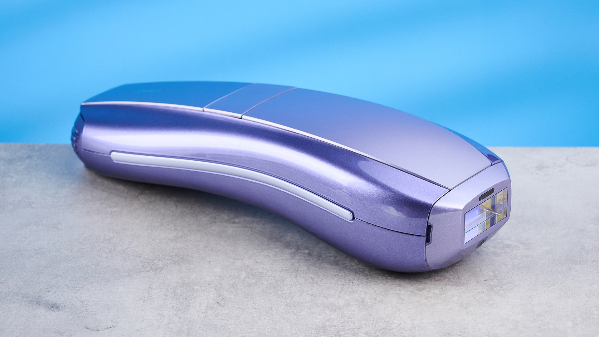 Hand holding the ULike Air 10 IPL machine photographed in front of a blue background.